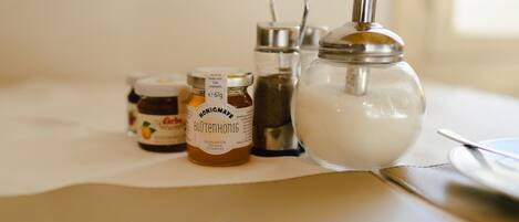 A table with three jars of honey and a sugar bowl.