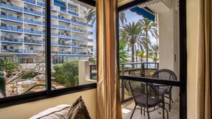 A balcony with a view of a multi-story building, outdoor furniture, and palm trees. - Skol 130 - 1-Bedroom Apartment with Sea Views in Marbella Centre (Marbella)