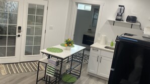 Cozinha compacta com área de refeições, ventilador de teto, iluminação embutida e uma pequena janela.