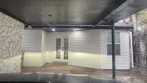 Uma garagem coberta com parede de pedra, porta branca e um poste de metal.