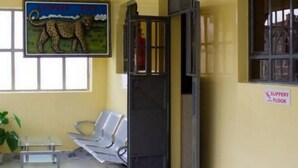 A waiting area with a leopard mural, a sign indicating a slippery floor, and a window with blinds. - Leopard View Hotel (Nakuru)