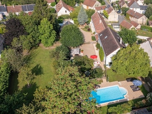 An aerial view of a residential area with a swimming pool, surrounded by houses and greenery.