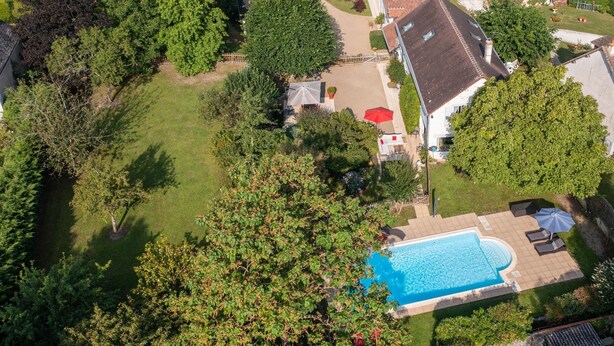 Vista aérea de uma área residencial com casas, piscina e vegetação ao redor.