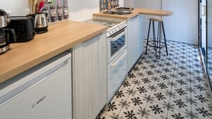 Uma cozinha moderna com armários brancos, uma pia de aço inoxidável e uma lava-louças Bosch.