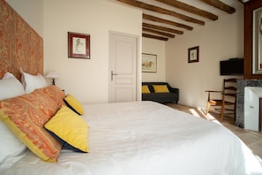 A bedroom with a large bed, a sofa, a television, and a door leading to another room. - Le Cottage du Cerf-Gîte-Ensuite with Shower (Francueil)