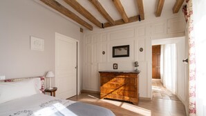 A bedroom with a bed, a dresser, and a door leading to another room.
