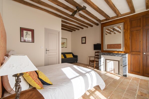 A bedroom with a bed, a lamp, a fireplace, and wooden beams on the ceiling. - Le Cottage du Cerf-Gîte-Ensuite with Shower (Francueil)