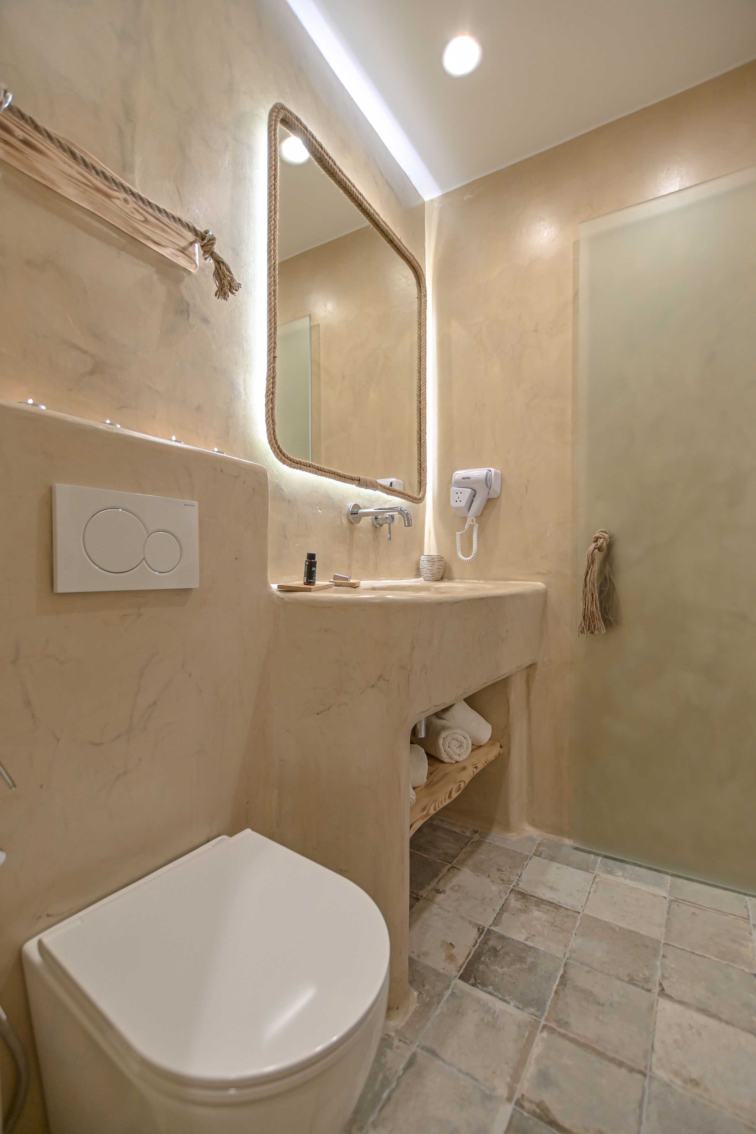 A bathroom with a toilet, sink, and mirror.