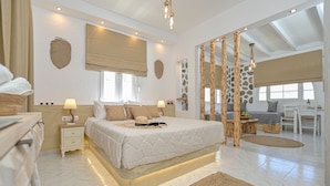 A spacious bedroom with a large bed, bedside tables, a desk, and a view of the outdoors. - Naxian Horizon (Naxos)