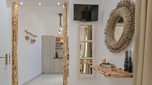 A modern interior with a wooden door, a TV mounted above a mirror, and a shelf with decorative items. - Naxian Horizon (Naxos)