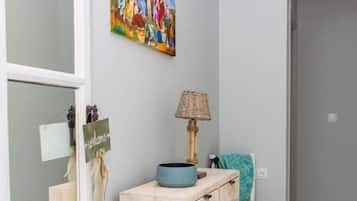 Un pasillo con una consola de madera, una lámpara, una silla y un cuadro en la pared.
