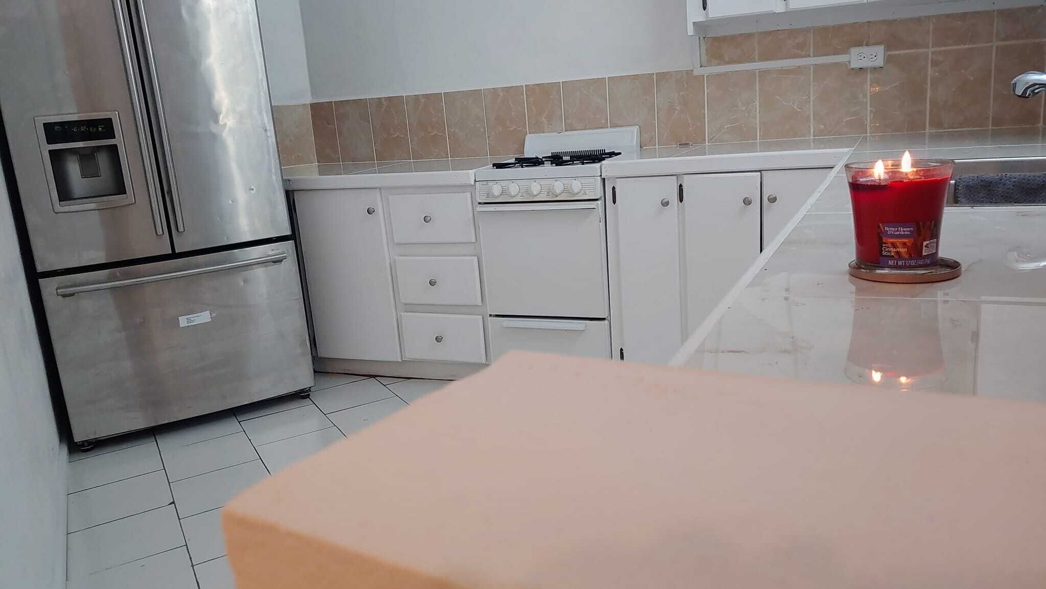 A modern kitchen with stainless steel appliances, white cabinets, and a tiled backsplash.