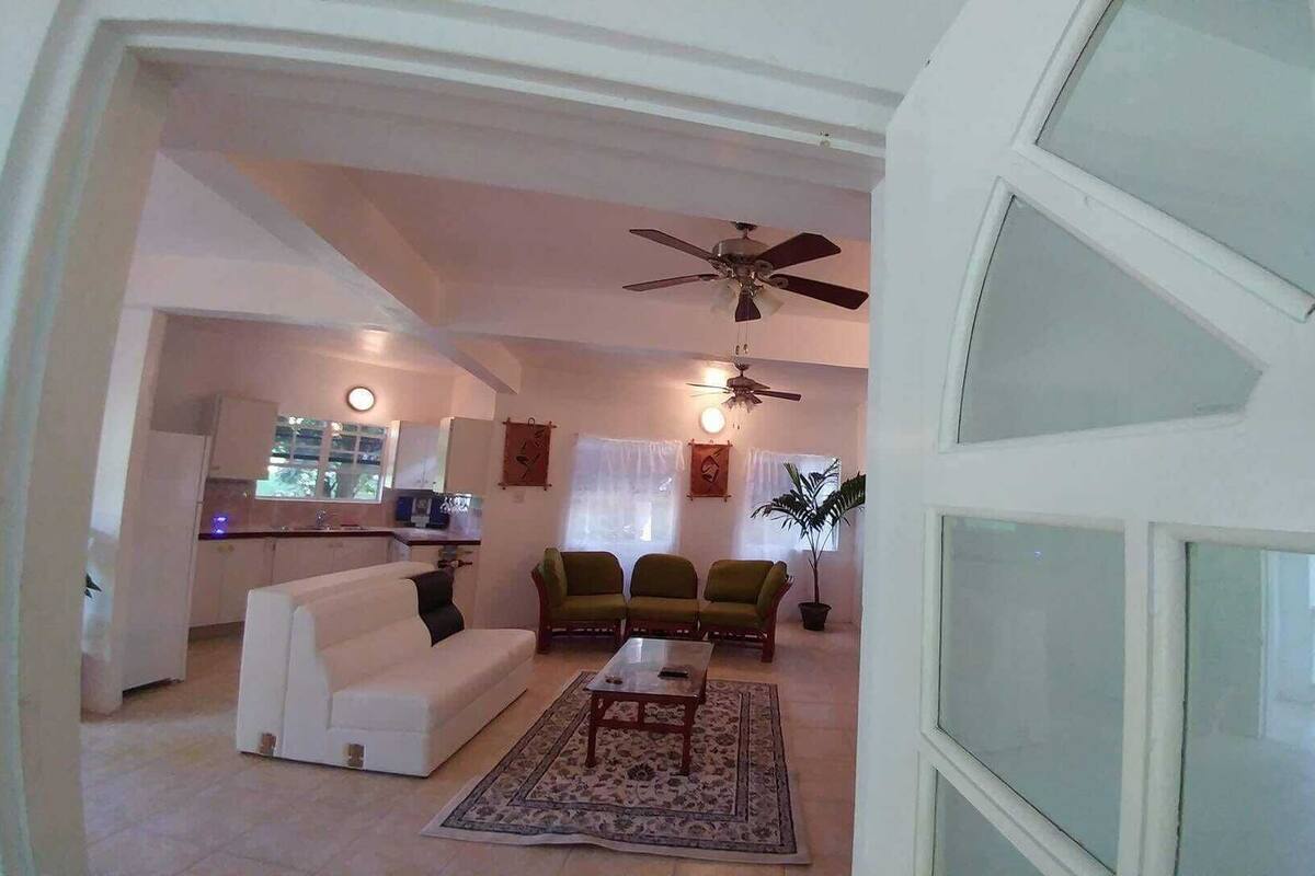 A living room with a sofa, chairs, a coffee table, and a ceiling fan.