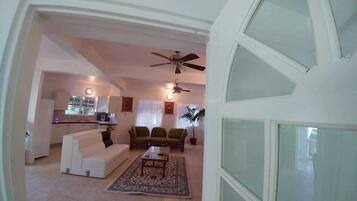 A living room with a sofa, chairs, a coffee table, and a ceiling fan.