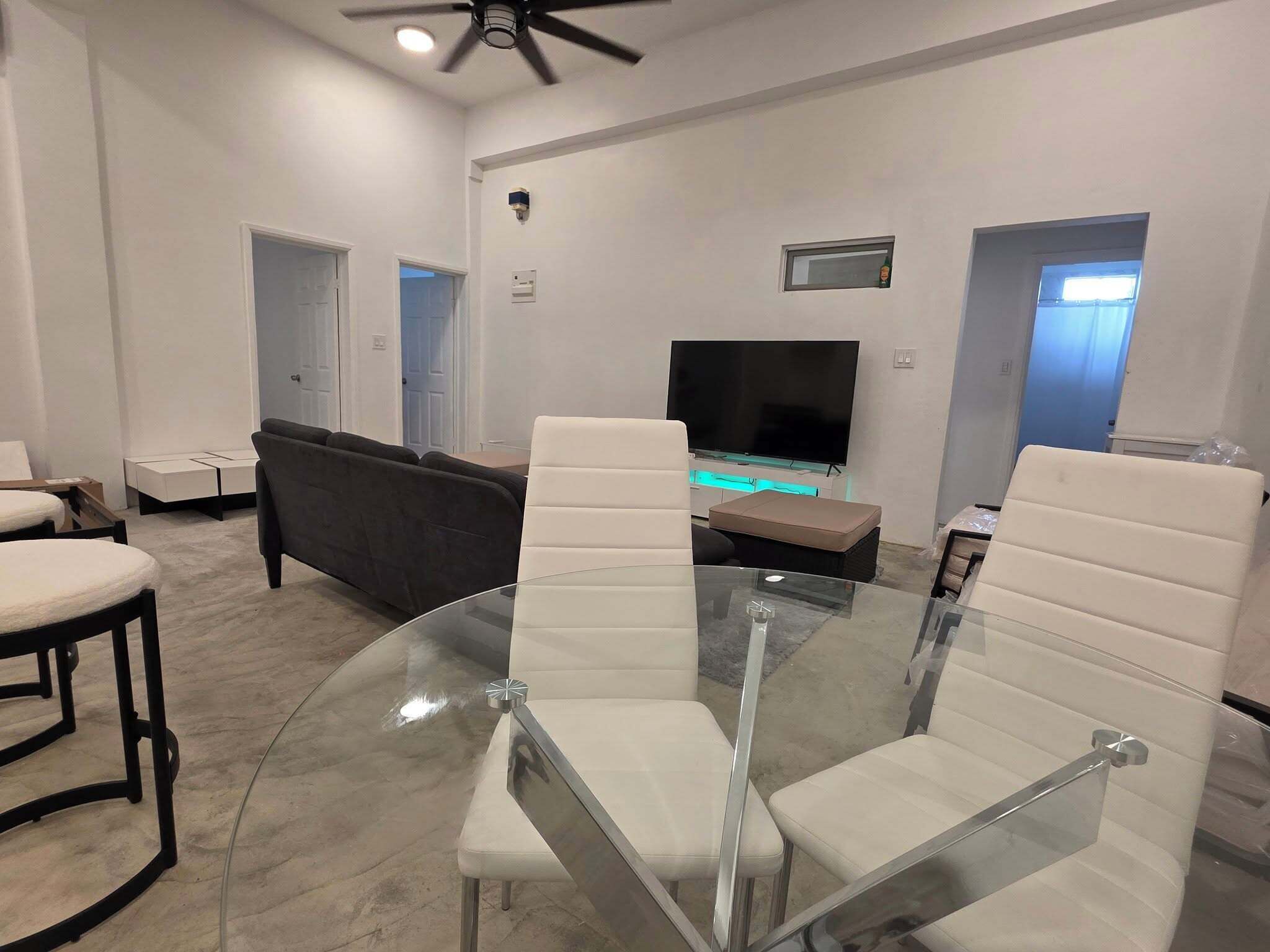 Un salon moderne avec une table basse en verre, un canapé et un téléviseur à écran plat.