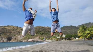 Guests can enjoy a lively beach scene with ocean views and a rocky coastline.