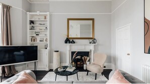 A living room with a fireplace, a television, a bookshelf, and a comfortable seating area. - The Portland Apartment, 2 beds with parking (Bath)