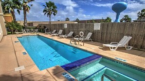 A rectangular pool with a 3 FT depth marking, surrounded by lounge chairs and a wooden fence. - Ground Floor Bayside Beauty Walk to the Beach (South Padre Island)