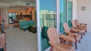 Een modern appartement met een woonkamer, keuken en balkon met houten stoelen.