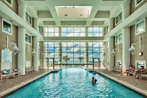 An indoor swimming pool with clear views of the sky through large windows, surrounded by lounge chairs and a tiled floor. - Gulf Views-Short Walk 2 Beach-Resort Amenities (Miramar Beach)