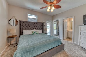 A bedroom with a tufted headboard, a large bed with a teal quilt, a ceiling fan, and a dresser with a mirror.