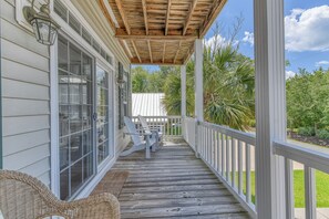 A wooden deck with a covered porch, white railings, and a wicker chair. - 4 Bedroom, 3 1/2 Bath Dog-Friendly Beach Home with Private Pool (Garden City Beach)