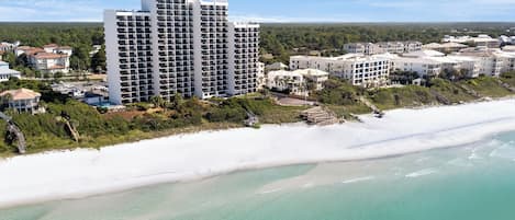 A coastal hotel with multiple high-rise buildings, a beachfront, and a view of the ocean.