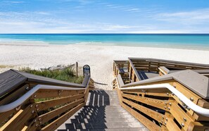 Ein hölzerner Steg führt zu Strandkörben aus Holz mit freiem Blick auf das Meer.