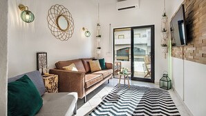 Uma sala de estar moderna com um sofá marrom, um tapete listrado e uma janela grande com vista para uma varanda.