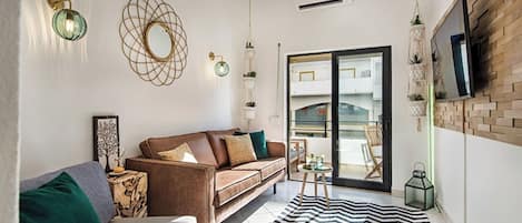 A modern living room with a brown sofa, a striped rug, and a large window with a view of a balcony.