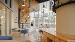 Un caffè moderno con arredi in legno, ampie finestre e luci a sospensione.