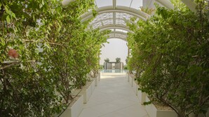 Un corridoio con una struttura moderna e geometrica al soffitto e composizioni floreali simmetriche su entrambi i lati.