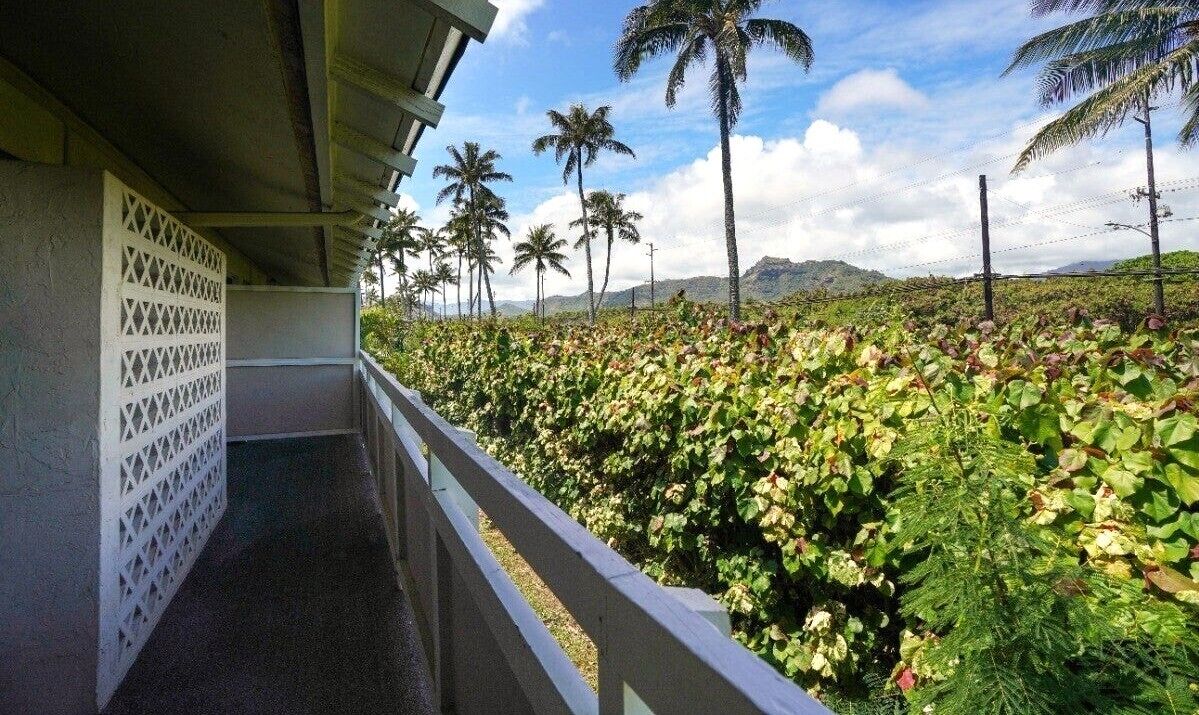 A balcony with a view of a lush garden and palm trees.