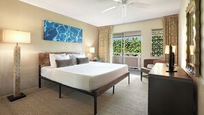 A hotel room with a bed, a desk, a ceiling fan, and a view of greenery outside. - Plantation Hale K10 | 1BR Condo w/ AC, Resort pool,  Private Lanai (Kapaa)