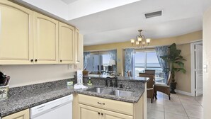 A kitchen with granite countertops, a dishwasher, and a dining area with a table and chairs. - 1 Bedroom, 1 Bath Gulf Front Condo t Regency Towers 603 East! (Pensacola Beach)
