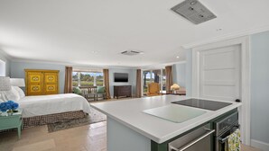 Eine moderne Küche mit Kochinsel, einem Essbereich mit Tisch und Stühlen, einem gelben Schrank und einem großen Fenster mit Blick ins Freie.