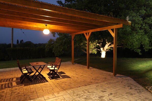 An outdoor patio with a wooden pergola, a table, and chairs.