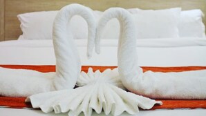 A hotel room with a neatly made bed, a painting on the wall, and a towel art arrangement on the bed. - Old Station Lounge Naivasha (Naivasha)