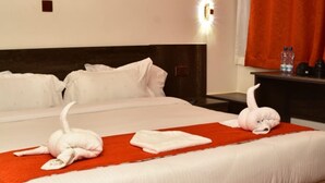 A hotel room with a large bed, a red rug, and a painting of a sunset on the wall. - Old Station Lounge Naivasha (Naivasha)