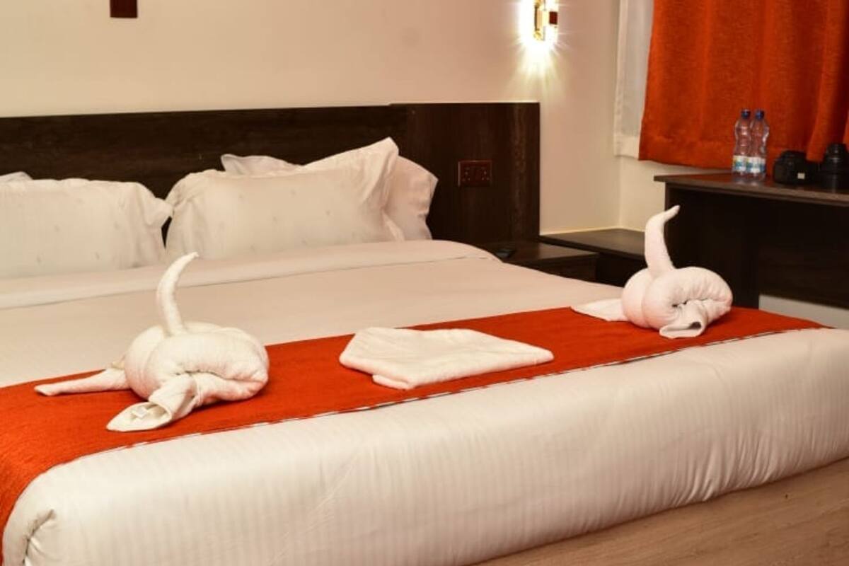Ein Hotelzimmer mit einem großen Bett, einem roten Teppich und einem Sonnenuntergangsbild an der Wand.