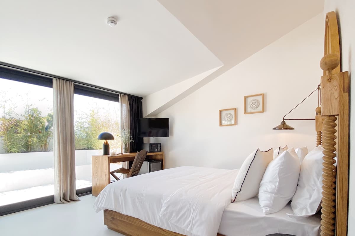A modern bedroom with a large bed, a desk, and a TV.