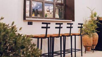 Un comedor con una mesa de madera larga y sillas negras, una ventana con varios paneles y luces colgantes.