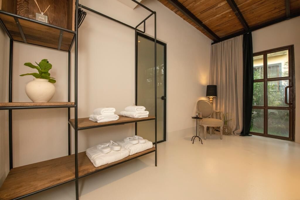 Una habitación moderna con techo de madera, puerta de cristal, una silla, una mesa y una planta en maceta.