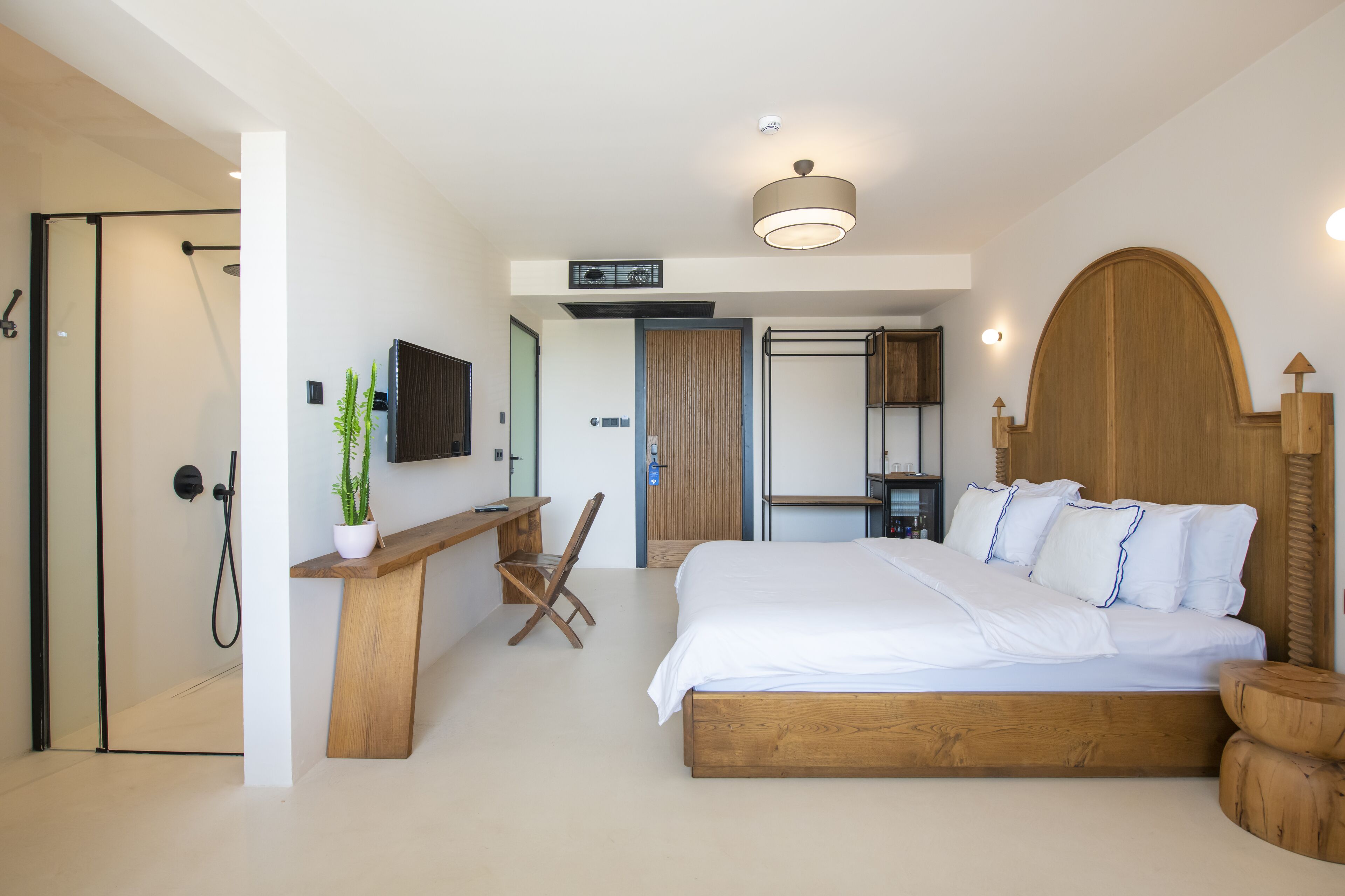 A modern bedroom with a wooden bed, a desk, and a shower.