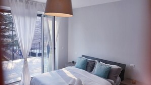 Une chambre d’hôtel avec un lit, une table de chevet, une lampe et une vue sur l’extérieur grâce à une grande fenêtre.