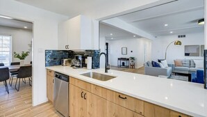 A modern kitchen with a large island, a dishwasher, and a built-in oven.