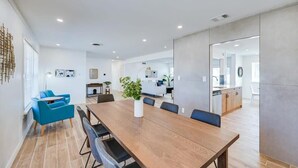 A modern dining area with a long wooden table, blue chairs, and a potted plant.