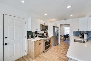 A modern kitchen with white cabinets, a stainless steel refrigerator, a microwave, and a stove.