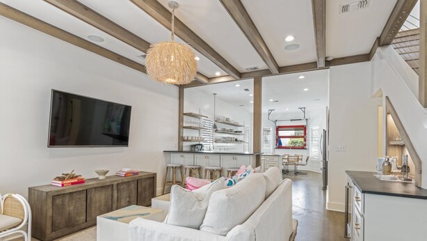 A modern living room with a white sofa, a TV mounted on the wall, and a wooden ceiling. - Bikes | Pool | Ping Pong | Beach Service (Santa Rosa Beach)
