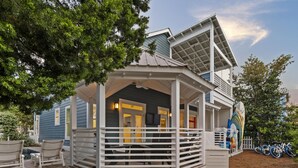 A two-story house with a covered porch, a garage, and a small outdoor seating area with chairs. - Bikes | Pool | Ping Pong | Beach Service (Santa Rosa Beach)
